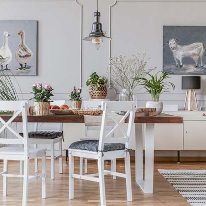 White and wooden furniture in a dining room setting surrounded by light grey walls
